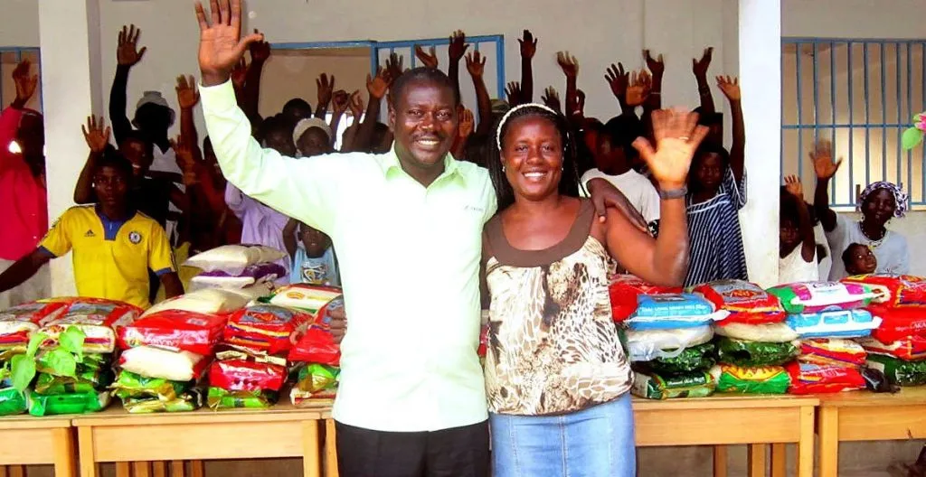 Aid workers smiling and waving with African villagers distributing food aid from Skanda Vale Ashram in the UK