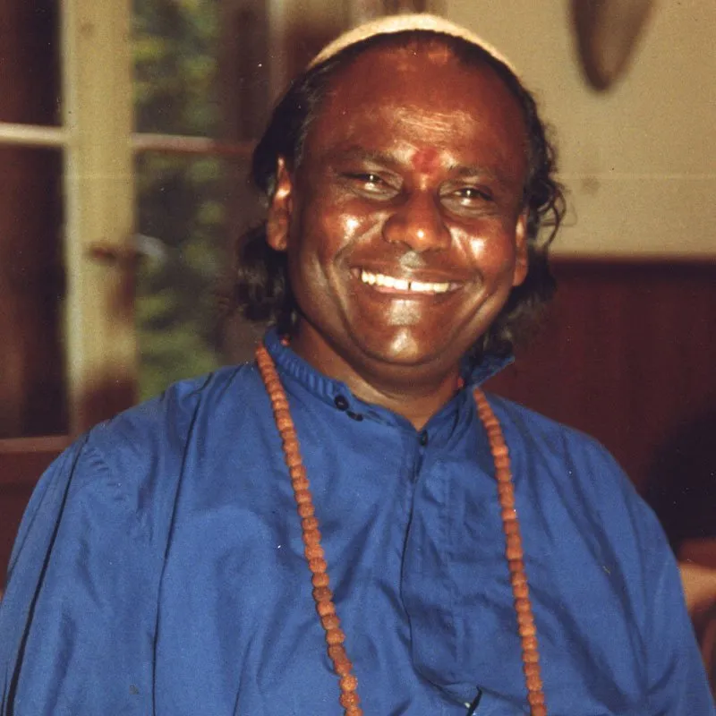 Guru Sri Subramanium smiling, wearing a blue robe and mala beads