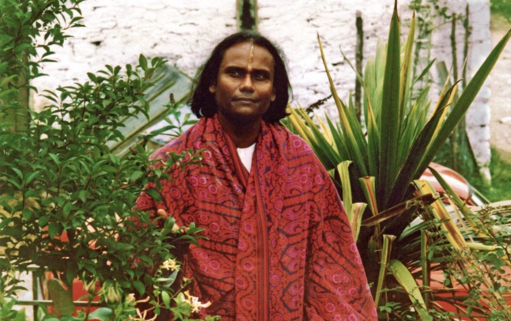 Guru Sri Subramanium in a red shawl in the gardens at Skanda Vale