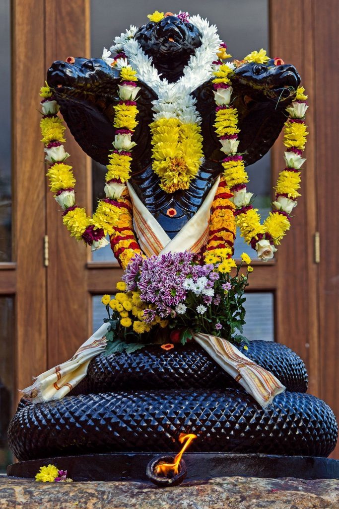 A murthi / idol of a three headed Naga, with flower garlands at Skanda Vale