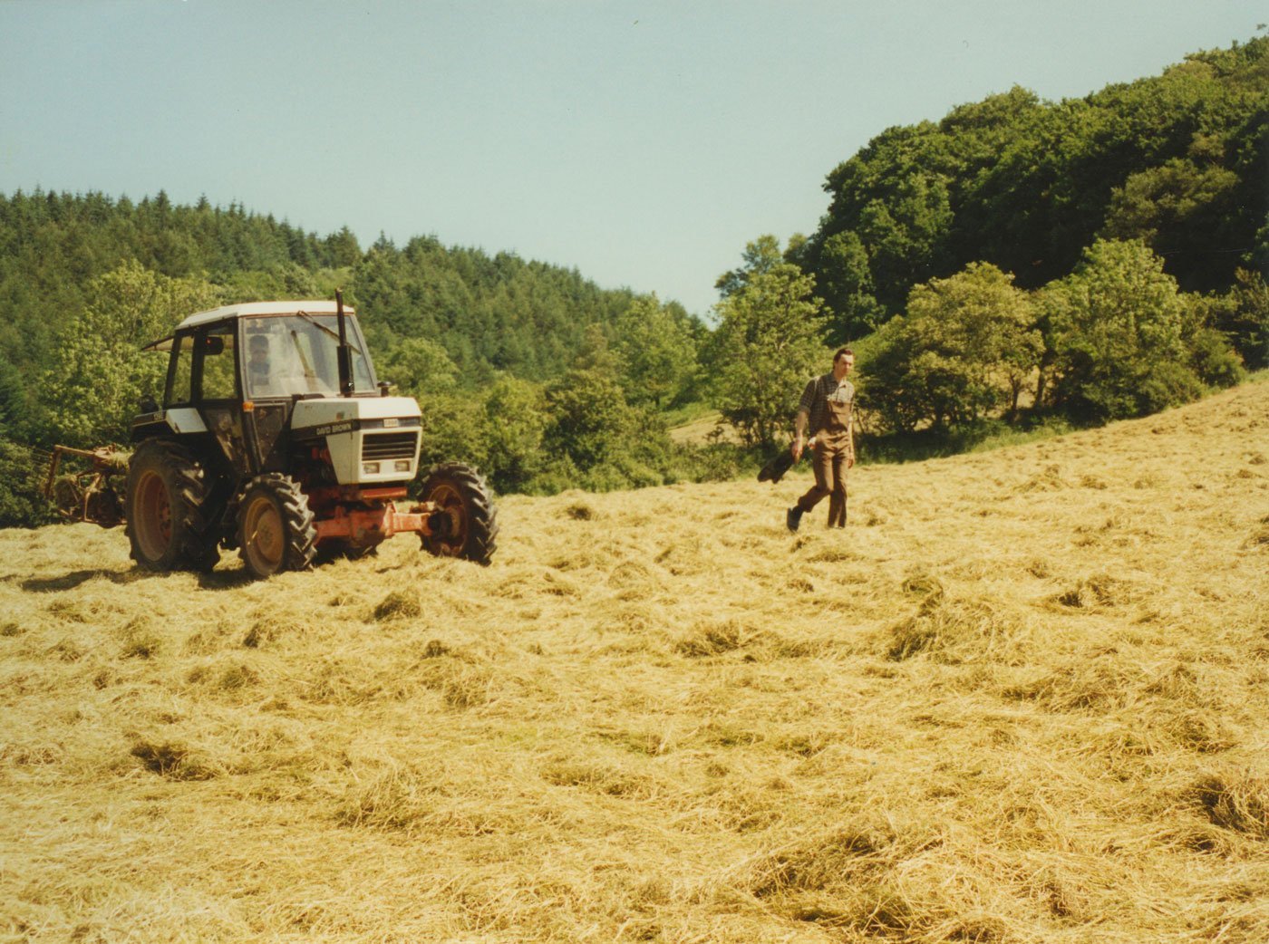 Monks in the fields of Skanda Vale cutting hay with a tractor