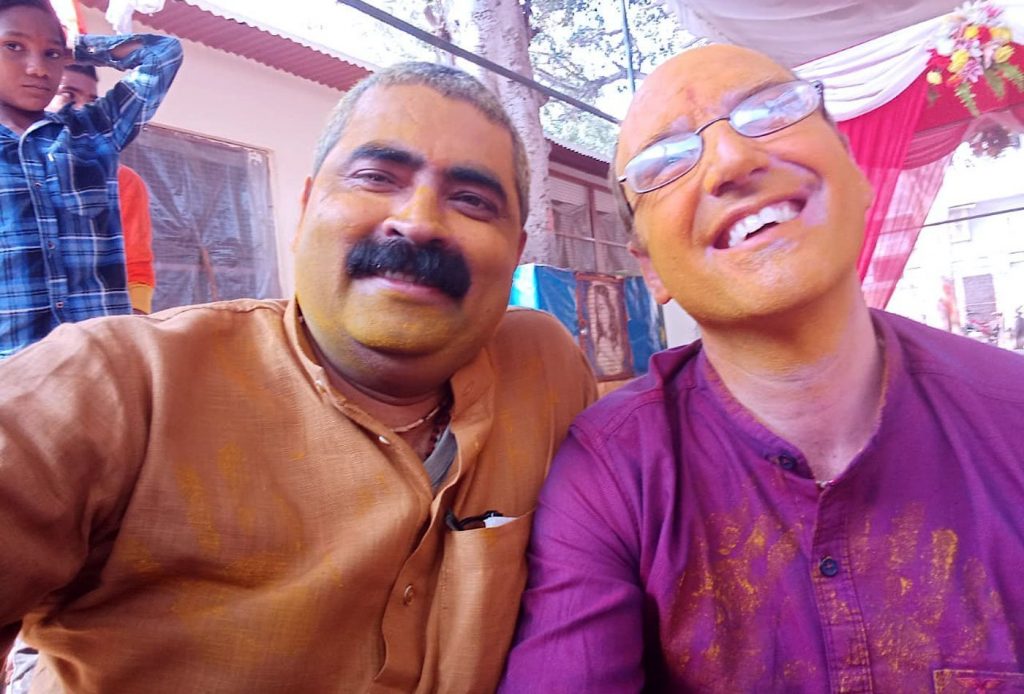 Swami Govinda and Indian man covered in paint, smiling