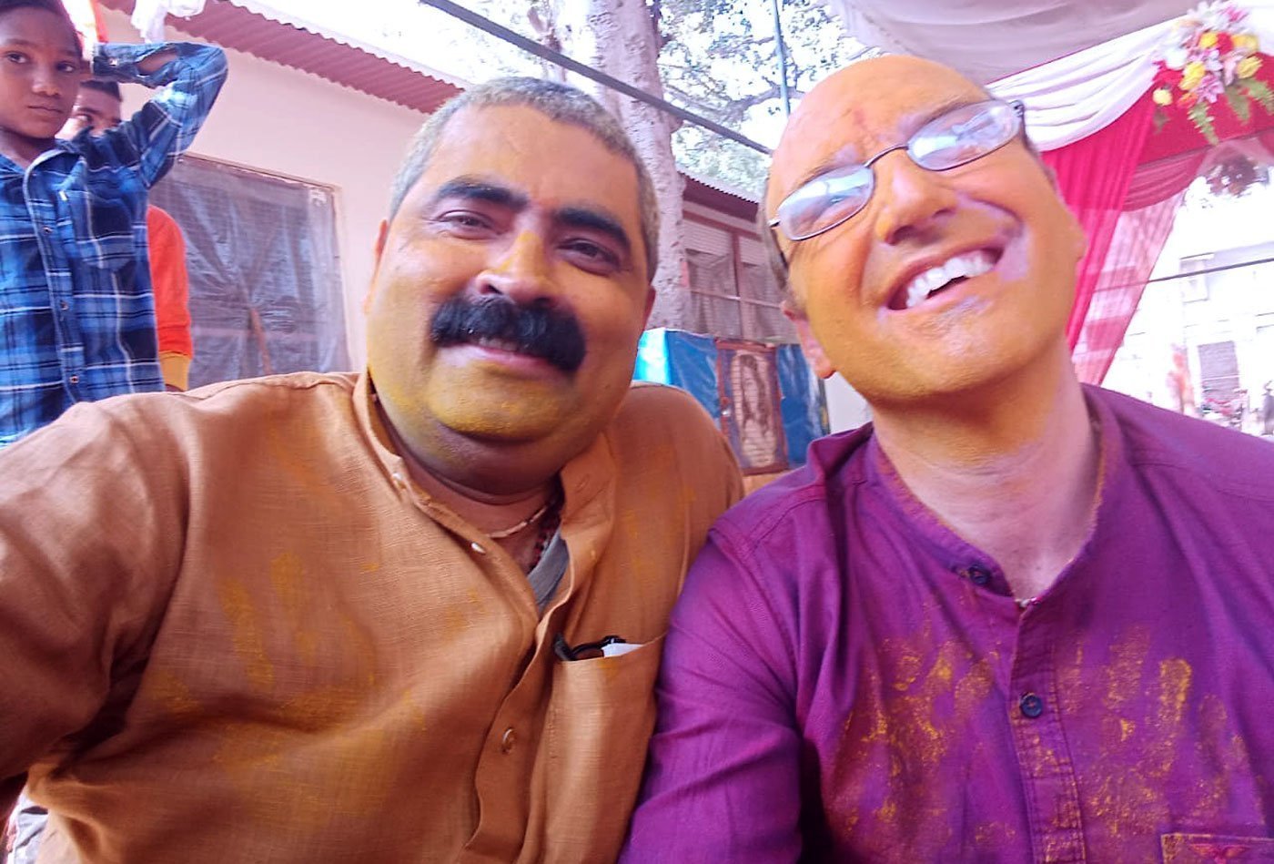 Swami Govinda and Indian man covered in paint, smiling
