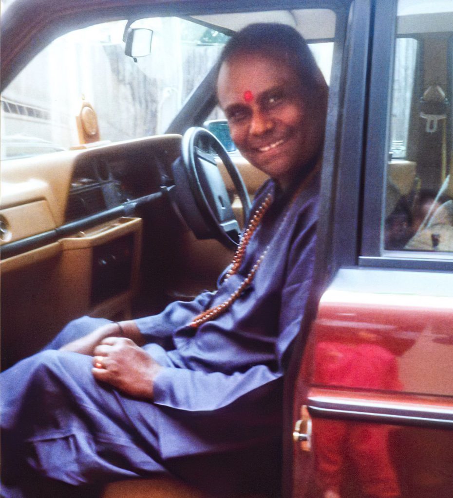 Guru sitting in a car smiling