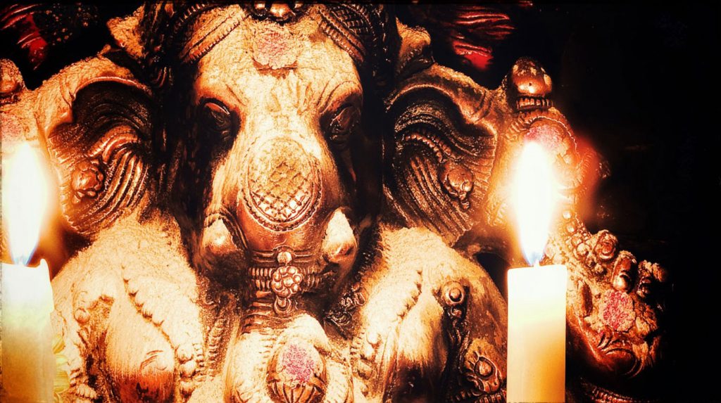 A murthi of Ganesh with vibhuti and a candle