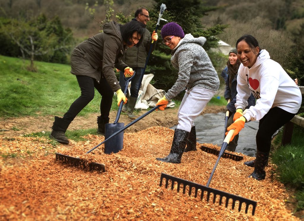 Volunteers raking wood chippings at Skanda Vale
