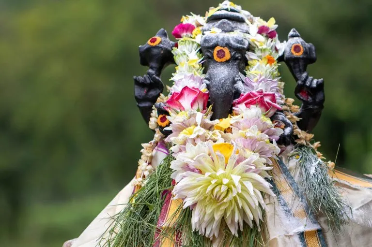 A murthi of Lord Ganesh with tilaks and flower garland