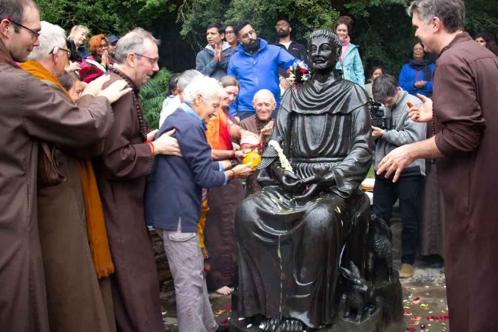 A group of monks and devotees consecrate a statue of St Francis of Assisi with holy water