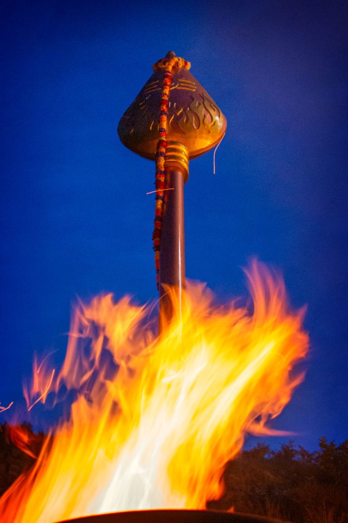 A large vel on top of a hill, lit by a firey deepam